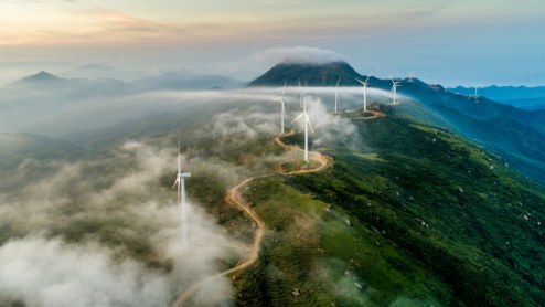 A solar wind farm on top of a mountain with a windy road